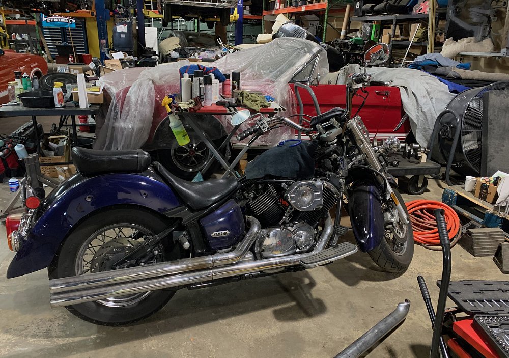 the blue V-Star in the full garage at J2J, with a car and other projects in the background