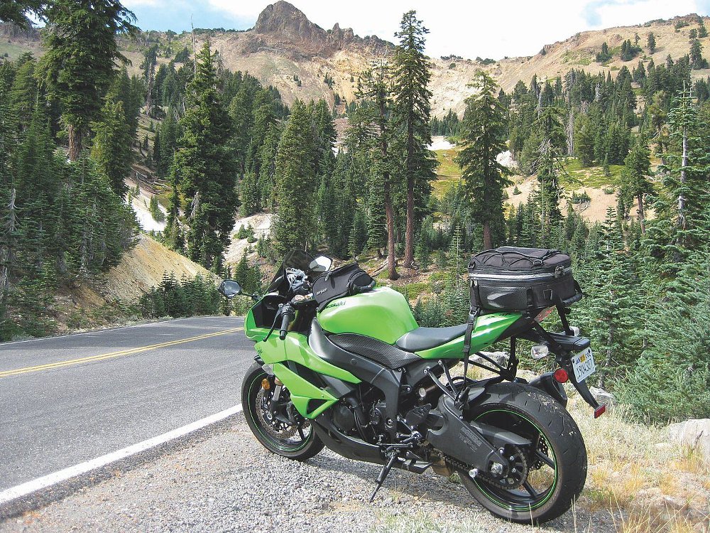 green Kawasaki sport bike parked along the curving road near the snow-covered volcanic mountain