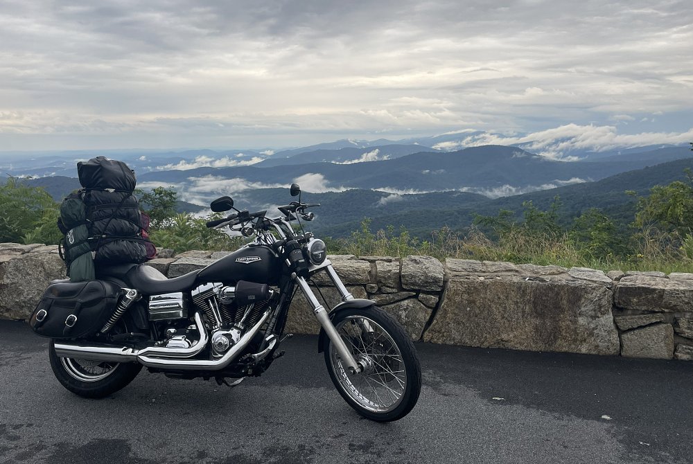 heavily packed Harley-Davidson motorcycle parked at a mountain overlook with fog in the valleys below